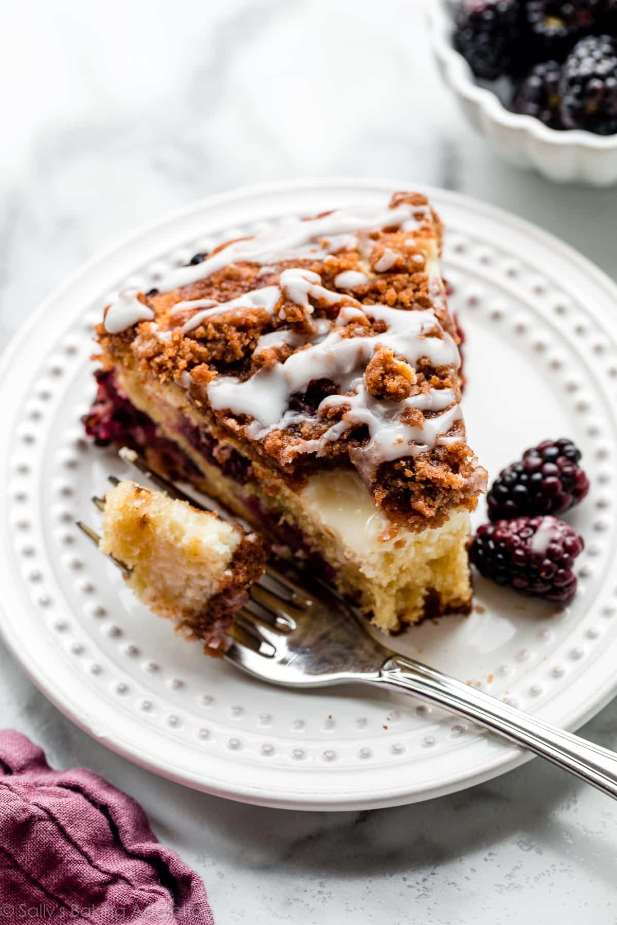 slice of blackberry crumb cake with cream cheese filling and lemon icing