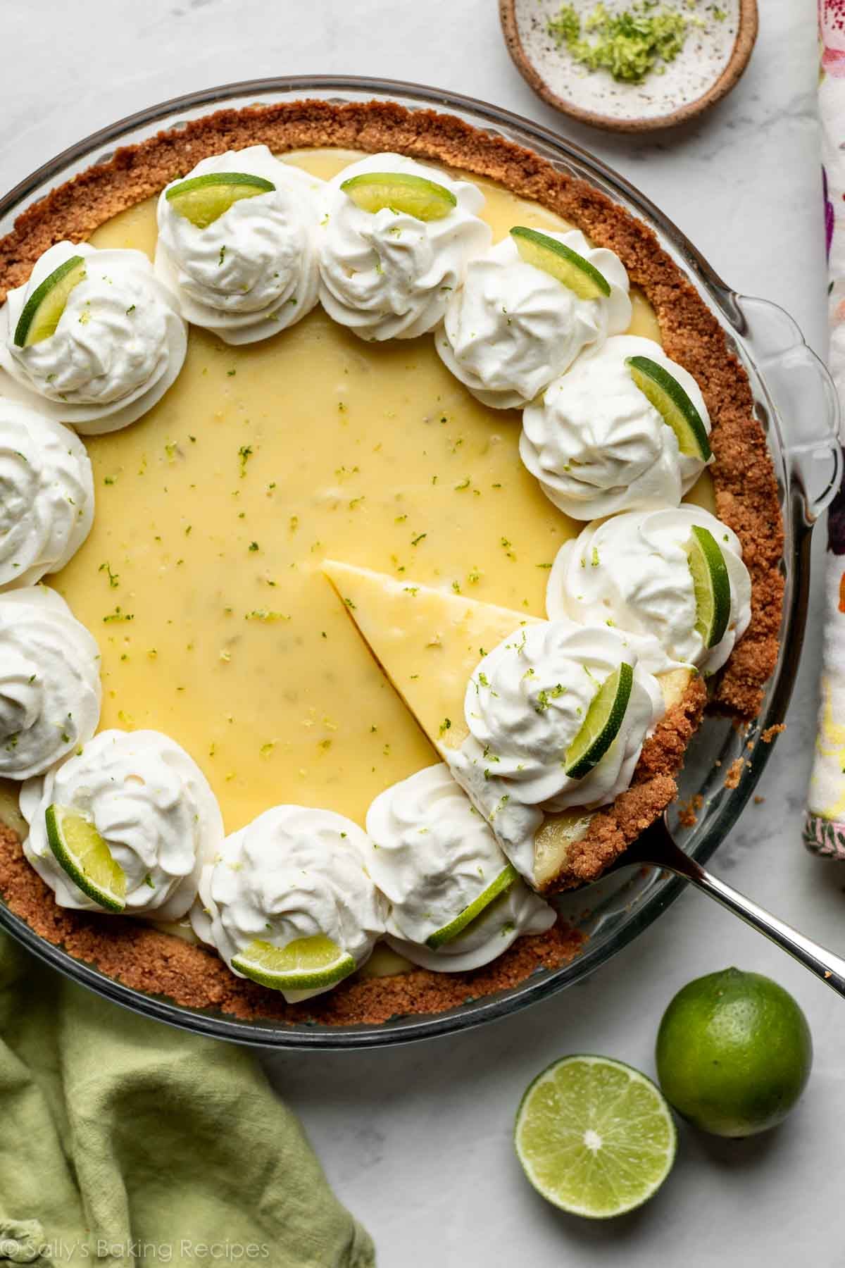 overhead photo showing slice of key lime pie being removed from glass pie dish.