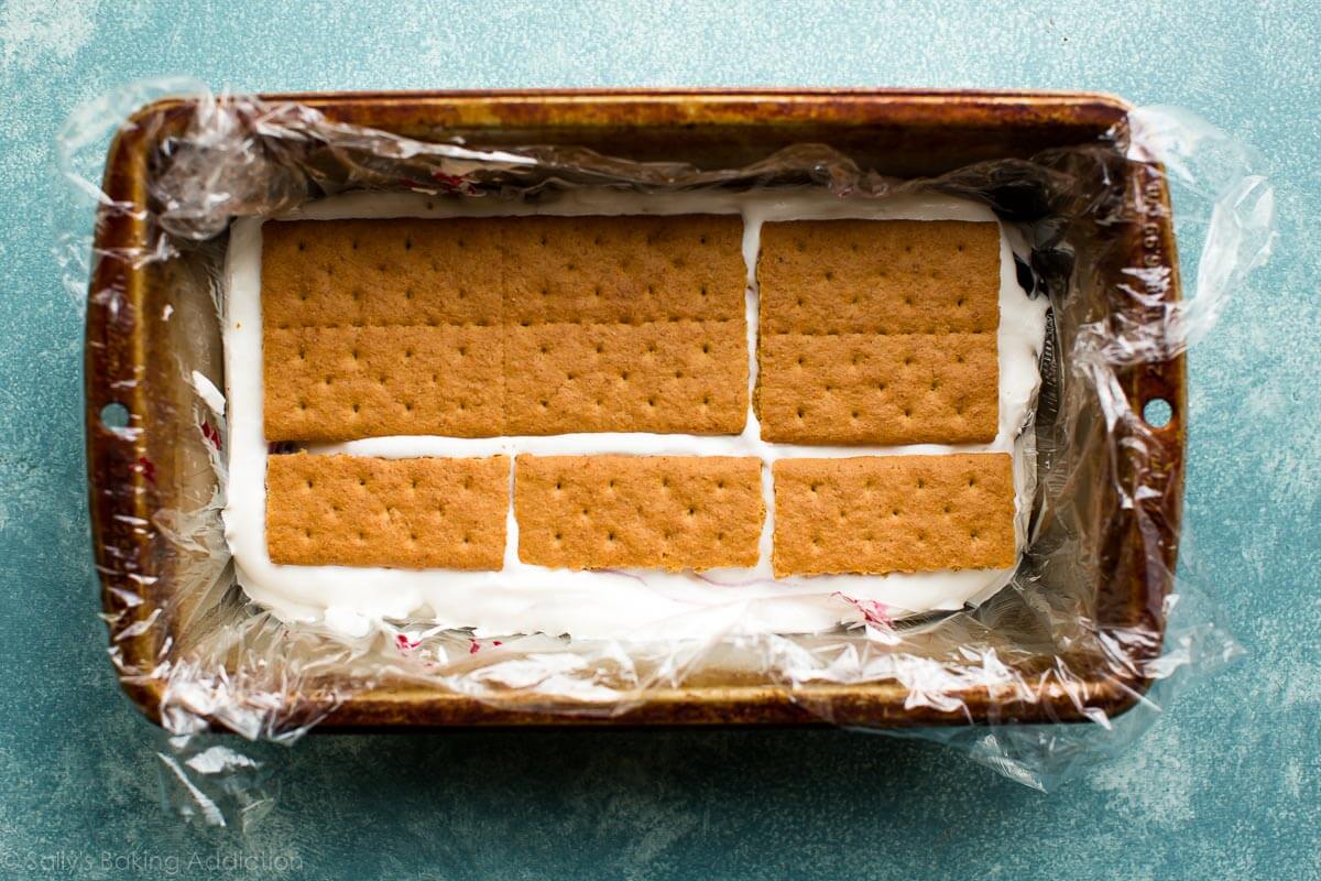 layer of graham crackers on top of whipped cream in a loaf pan