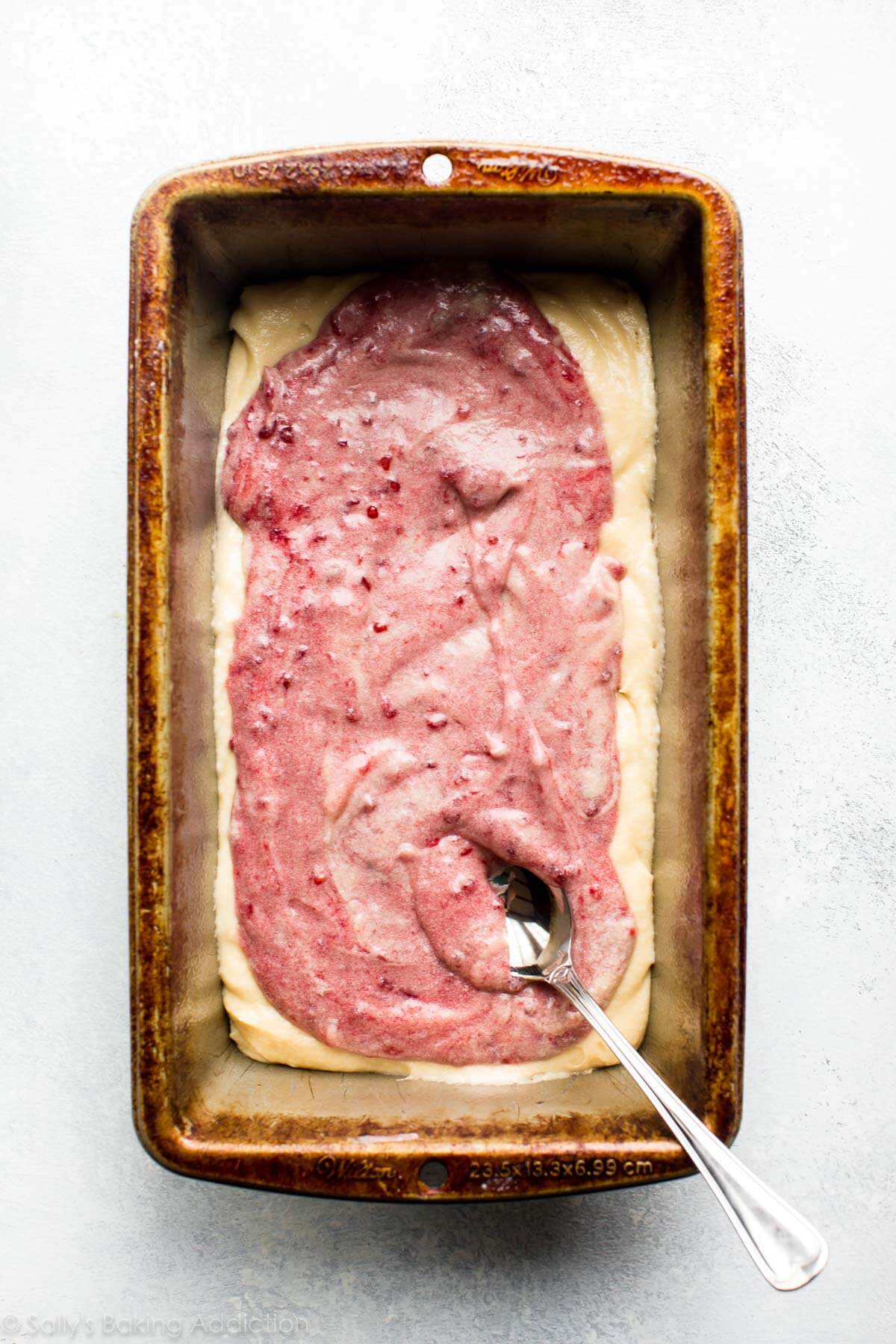 layer of raspberry swirl batter on top of layer of pound cake batter in a loaf pan