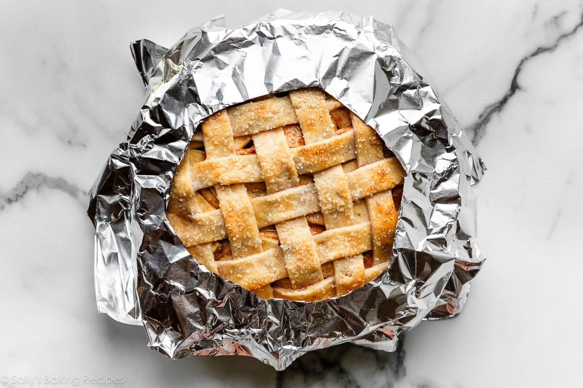 apple pie with lattice crust top shown with aluminum foil placed just on pie's edges.