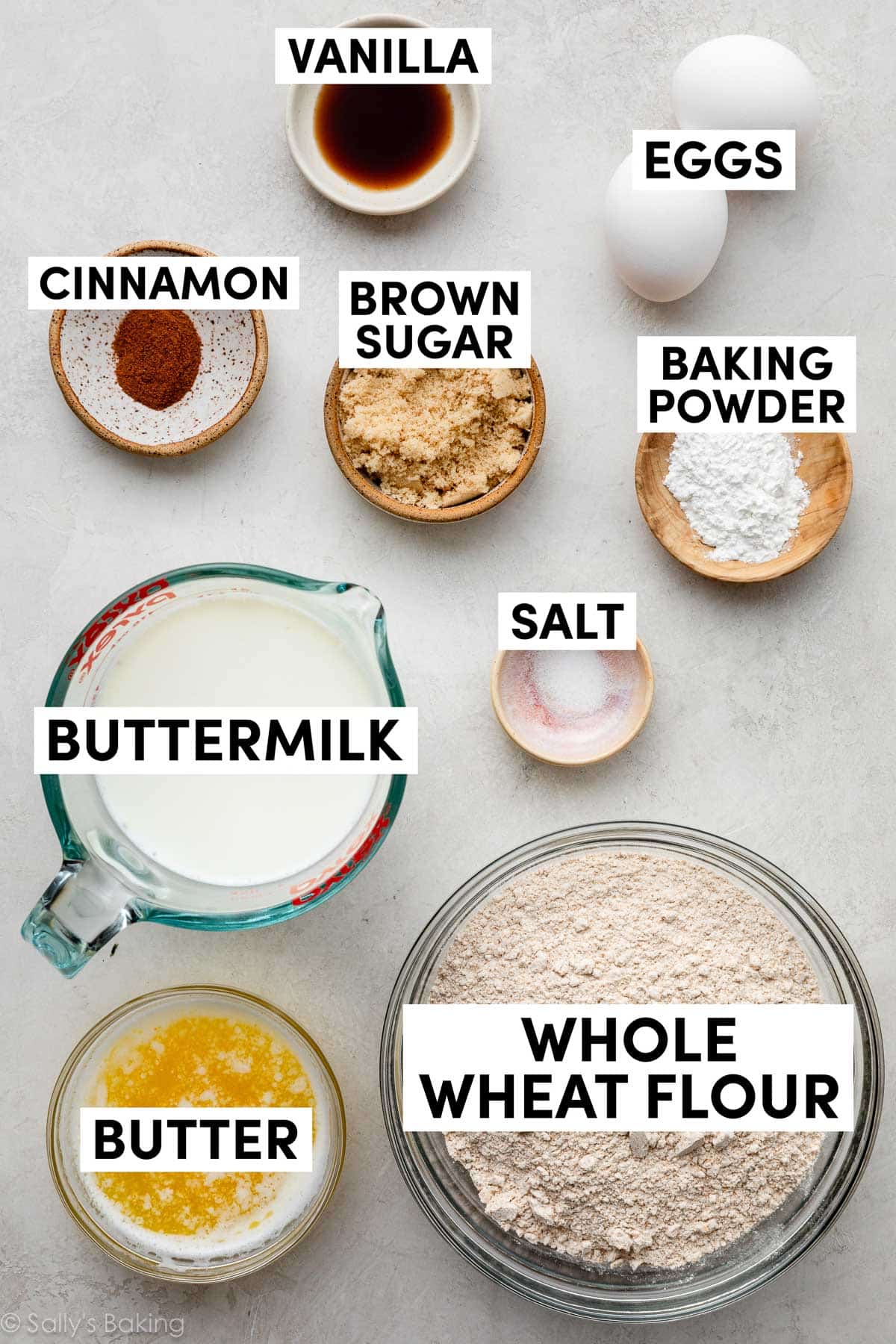 ingredients in bowls including vanilla, eggs, baking powder, brown sugar, cinnamon, butter, and buttermilk.