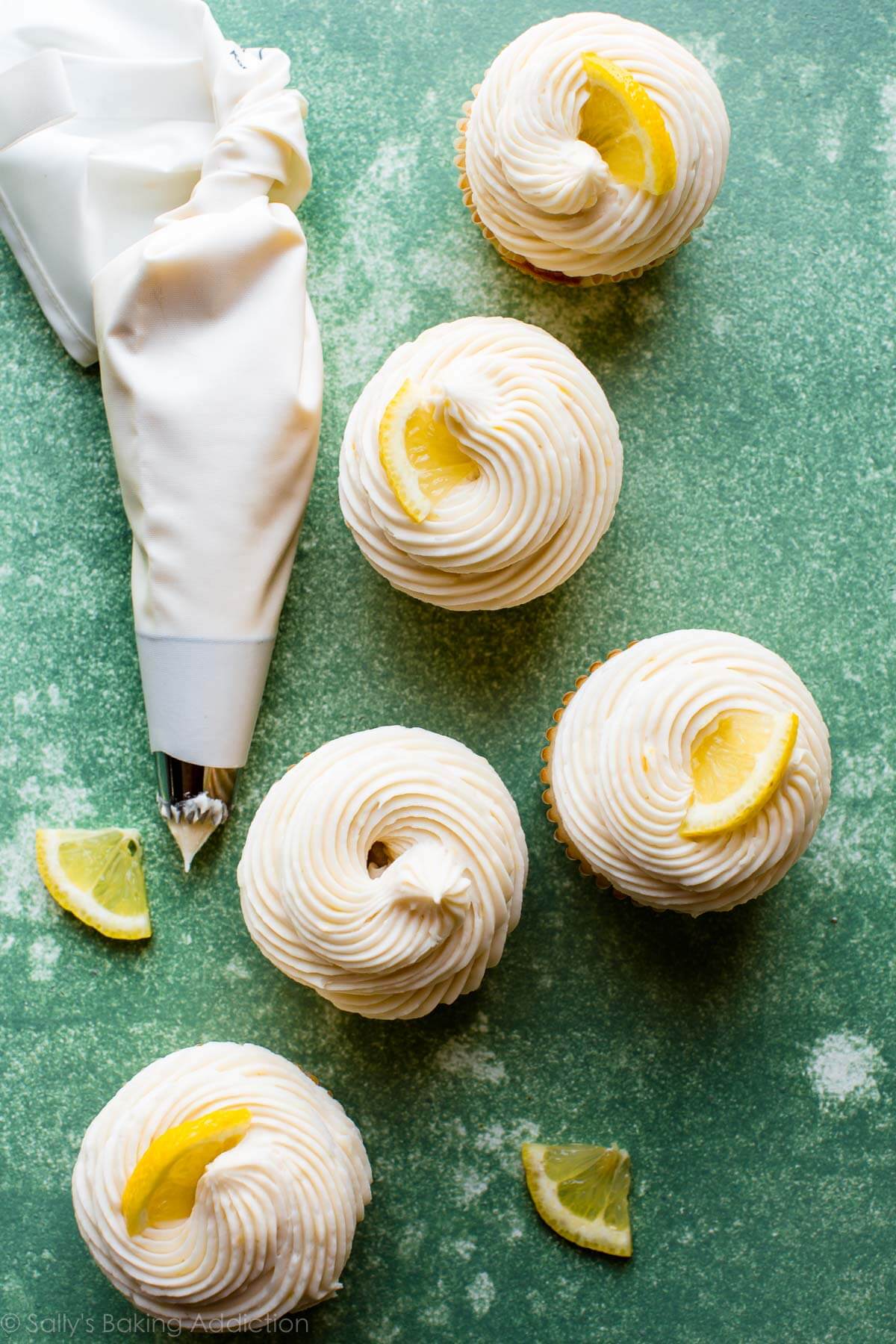 overhead image of lemon buttercream frosting piped onto cupcakes and topped with lemon slices