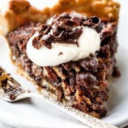 slice of dark chocolate pecan pie on a white plate