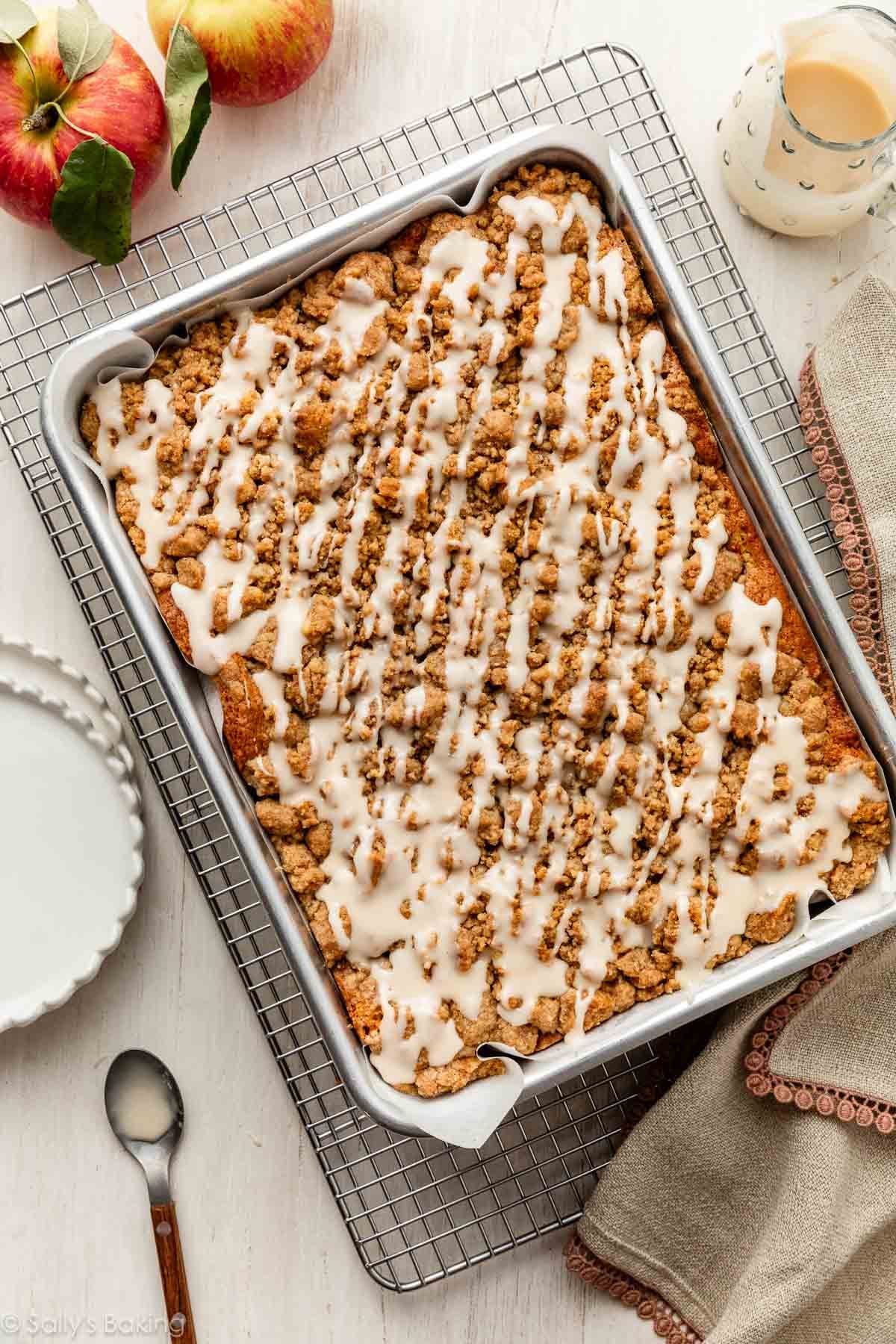 apple crumb cake in metal sheet pan with icing on top.