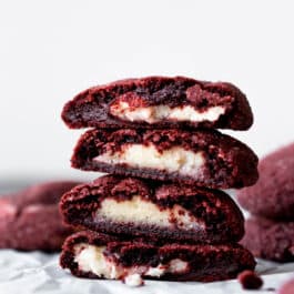 stack of cream cheese stuffed red velvet cookies showing the inside filling