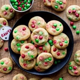 mini M&M cookies with Christmas M&Ms on a black plate with a Santa tag