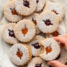 linzer cookies with raspberry and apricot jam on platter.