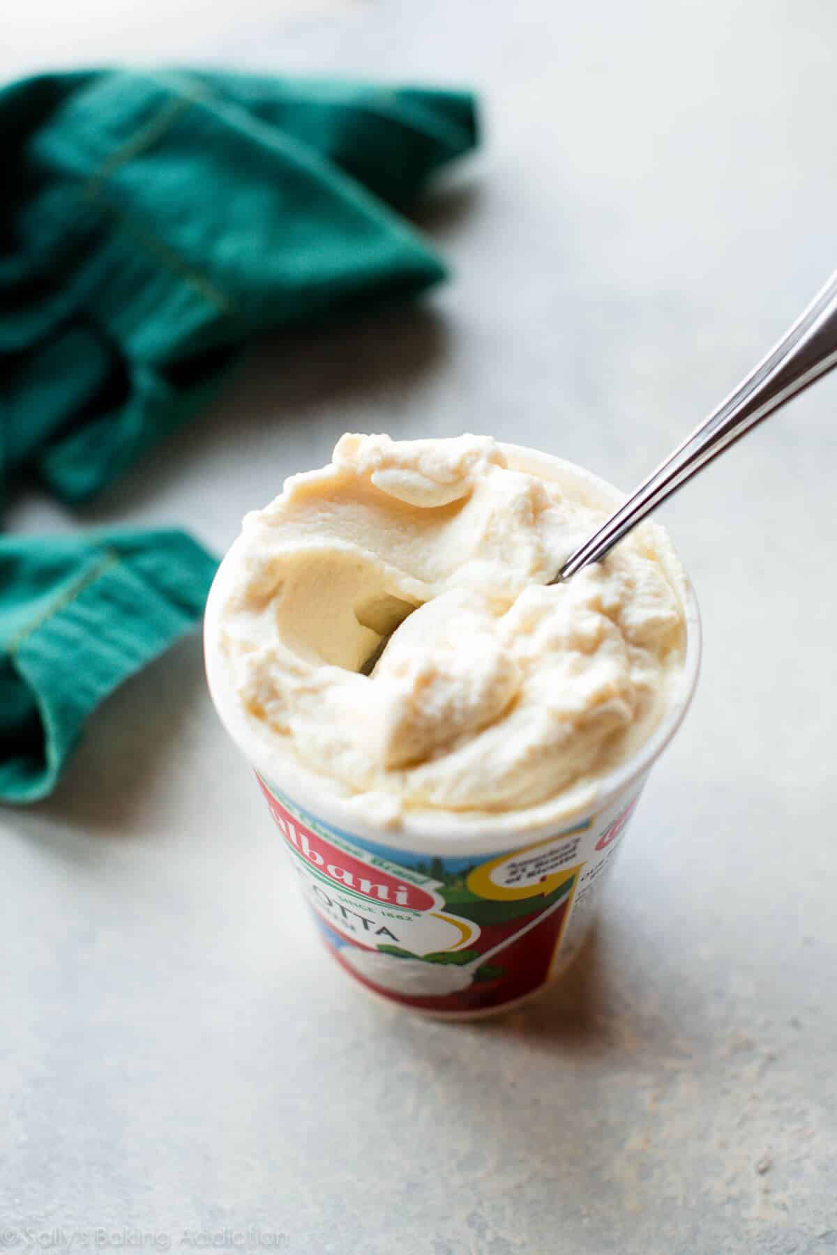 container of ricotta with a metal spoon