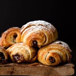 stack of chocolate croissants on a wood serving tray