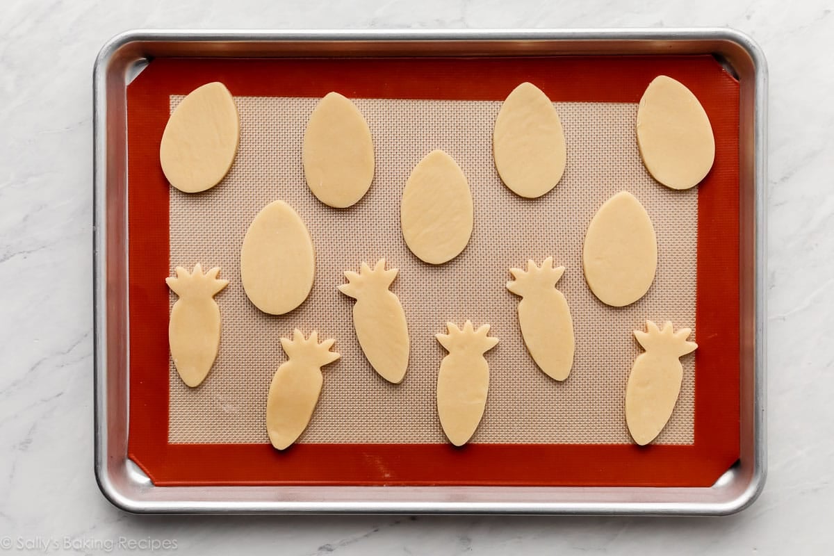 lined baking sheet with Easter egg and carrot-shaped cookies on top.