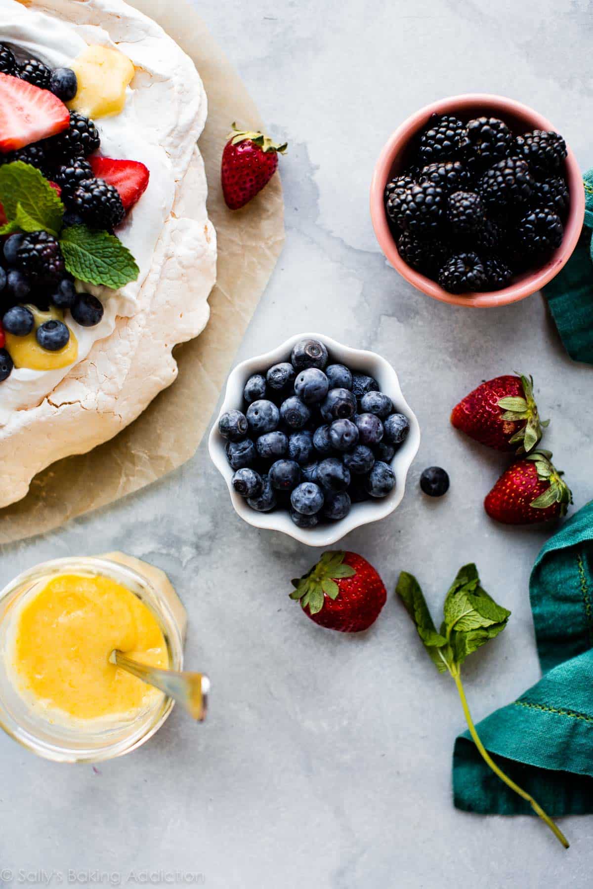 pavlova toppings including fresh berries and lemon curd in bowls