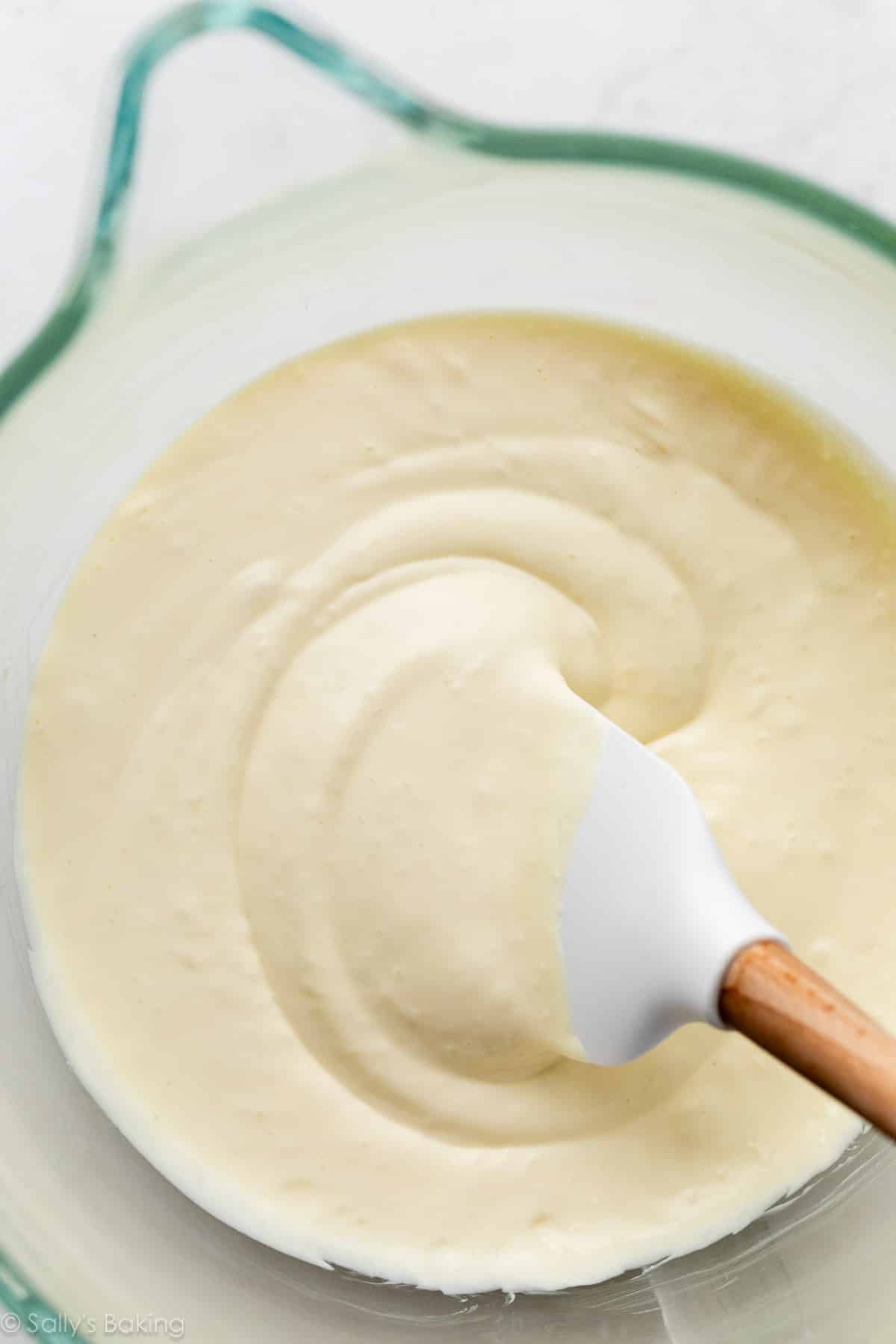 creamy batter in glass mixing bowl with white spatula.