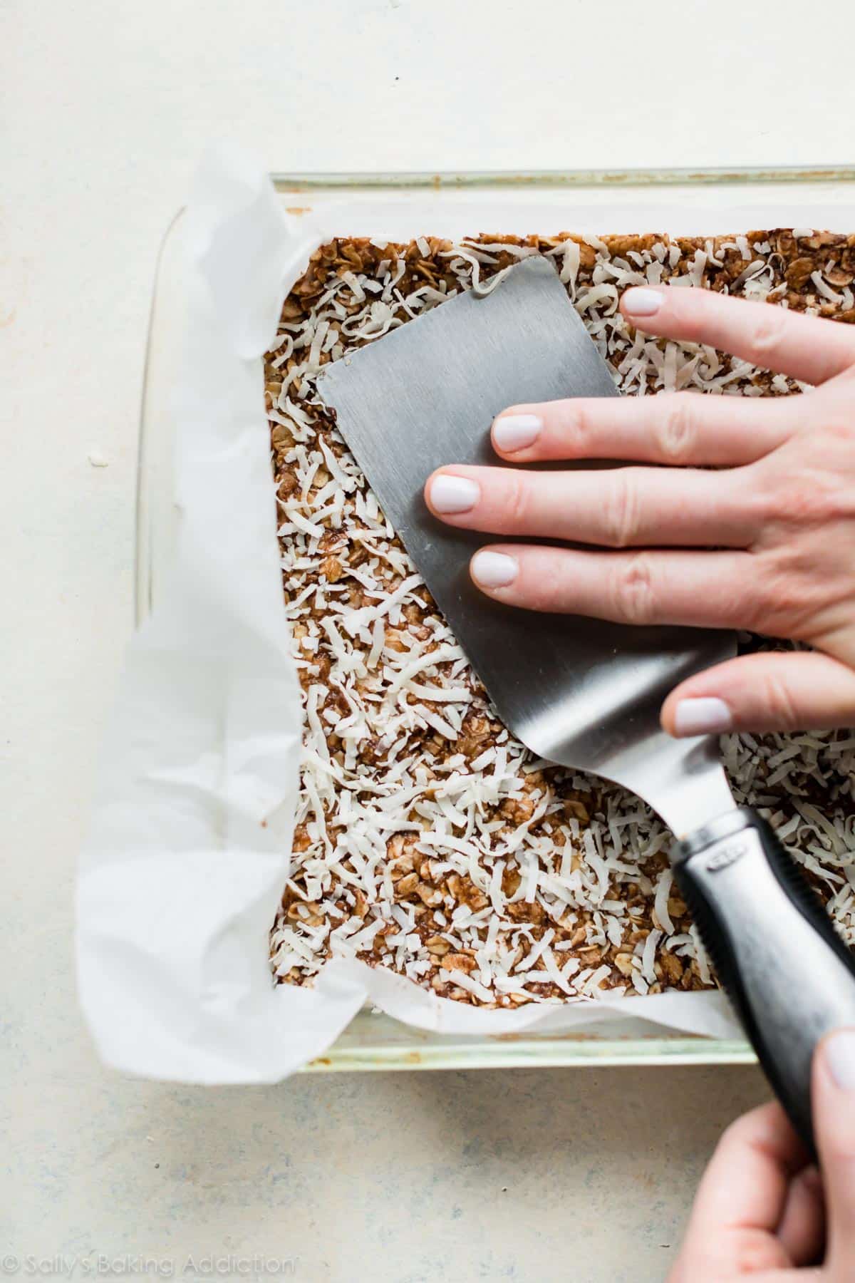 pressing granola bar mixture into a pan with a spatula