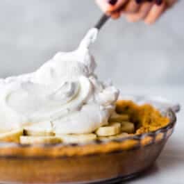 spreading fluffy homemade whipped cream on banoffee pie