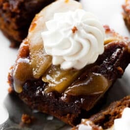Slice of upside-down pear gingerbread cake topped with whipped cream