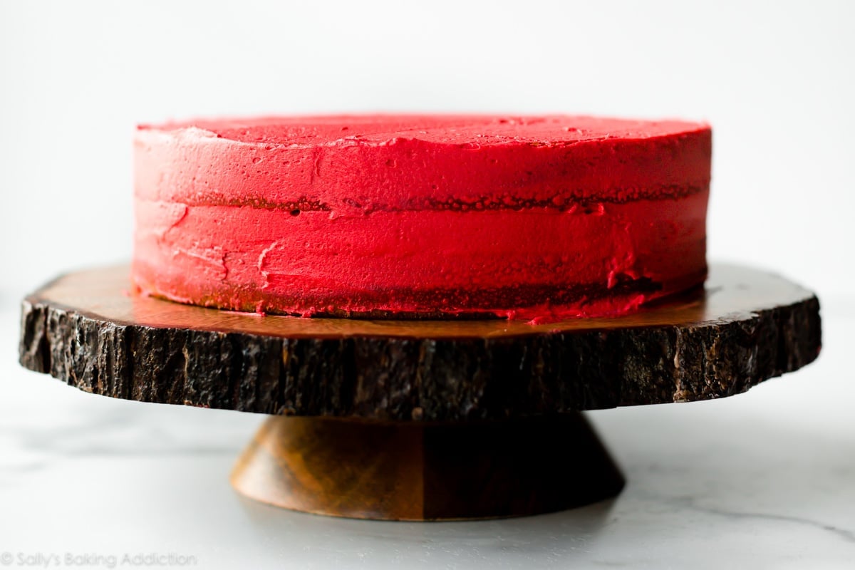 red crumb coated cake on a wood slice cake stand