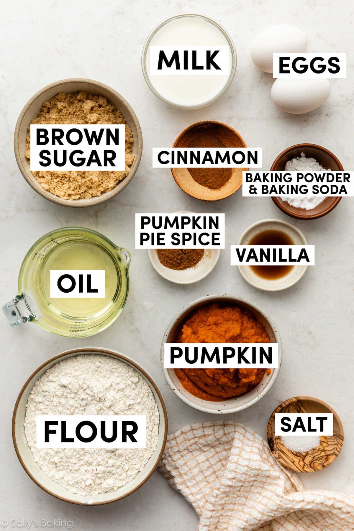 ingredients in bowls including flour, pumpkin, milk, cinnamon, vanilla, and oil.