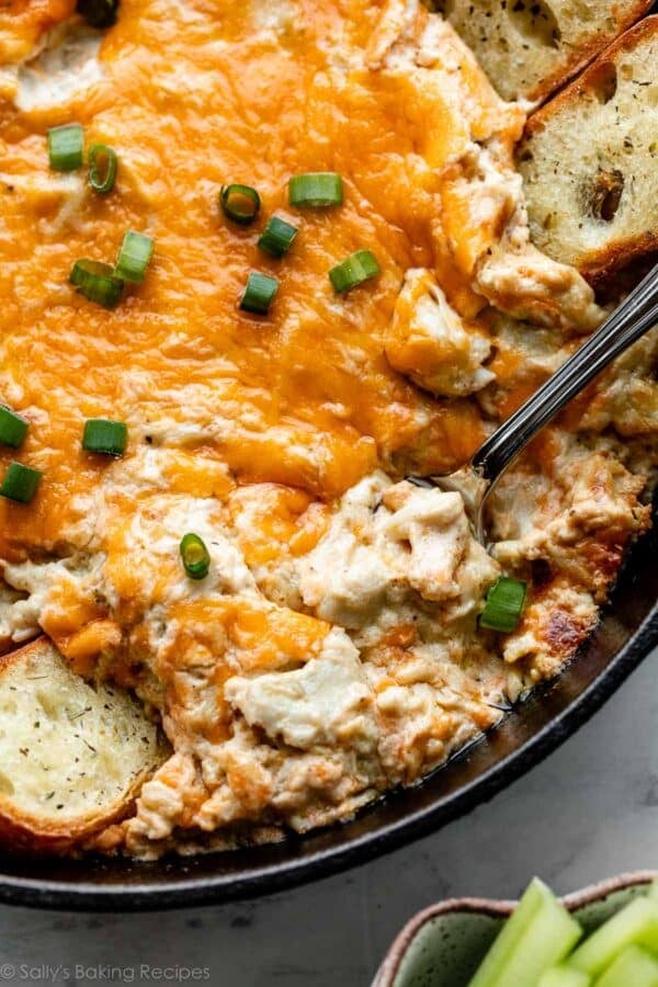 Maryland crab dip in cast iron skillet with green onion garnish on top.
