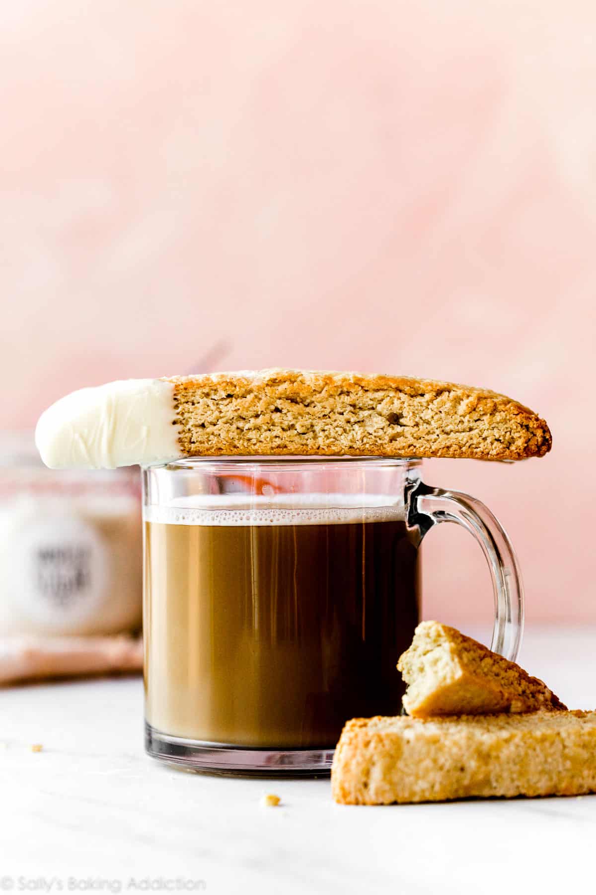 vanilla biscotti cookie dipped in white chocolate sitting on top of a mug of coffee