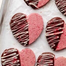 heart-shaped raspberry Valentine's Day cookies dipped in chocolate and drizzled with white chocolate.