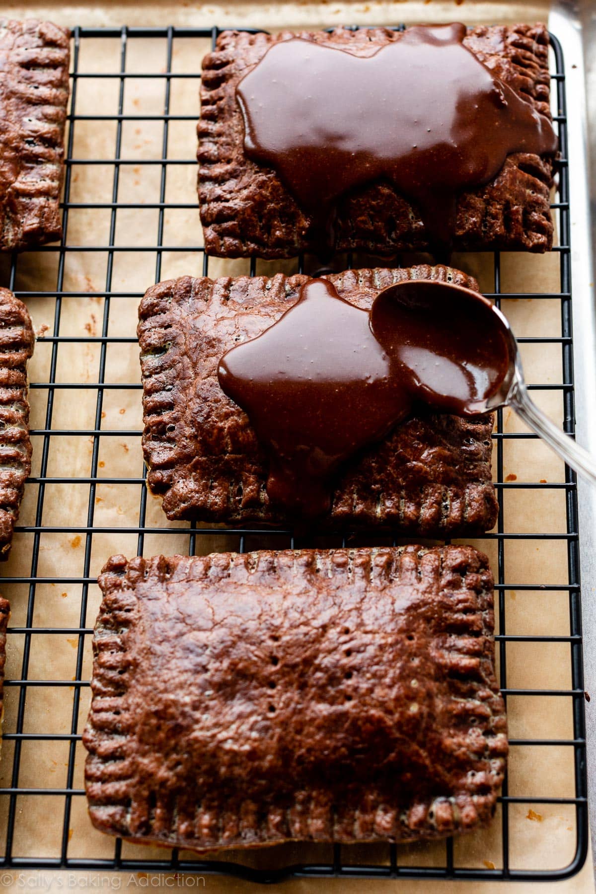 spooning chocolate icing on top of baked chocolate pastry pop tarts