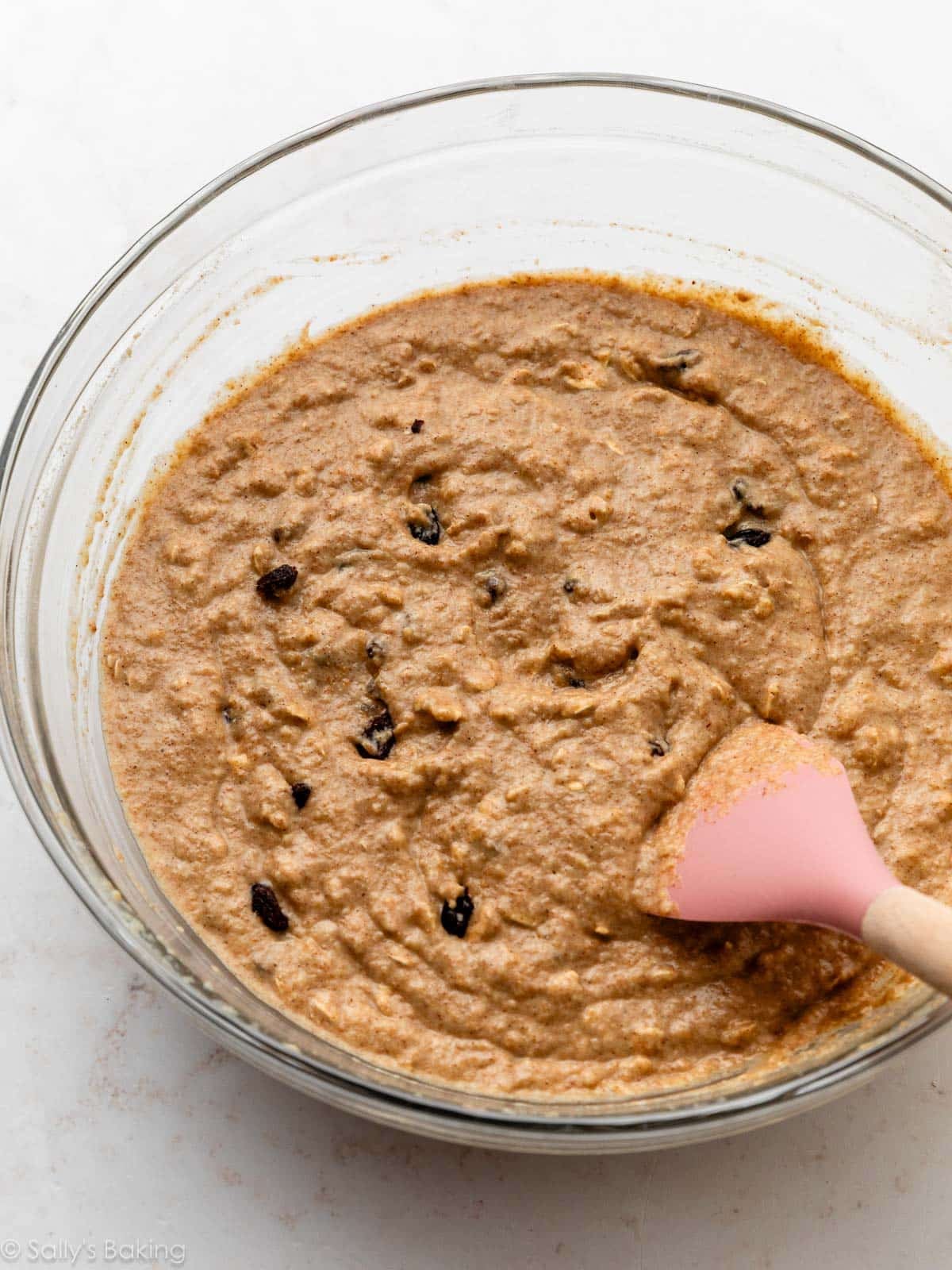 muffin batter in glass bowl with pink spatula.