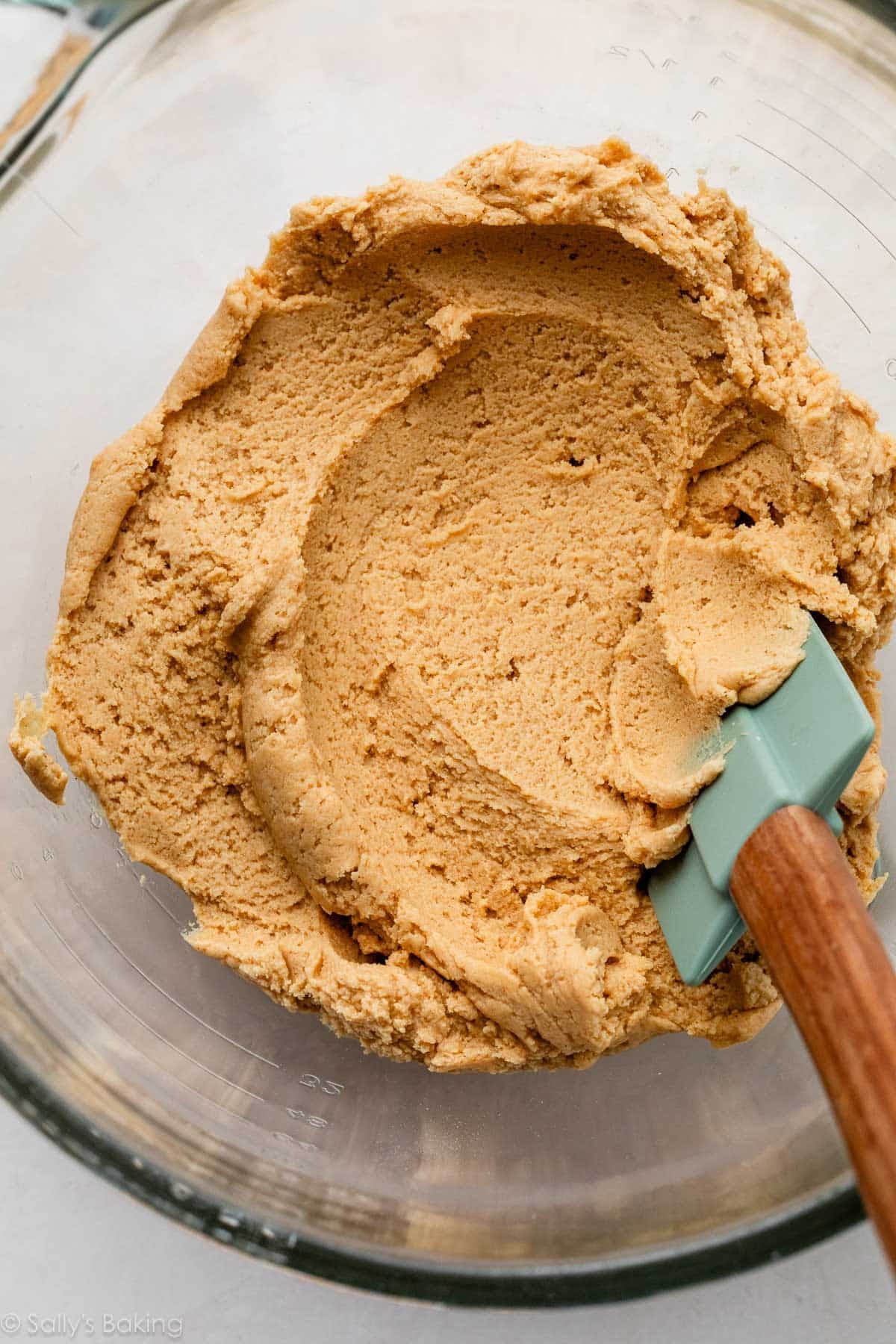 super soft cookie dough in glass bowl with green spatula.