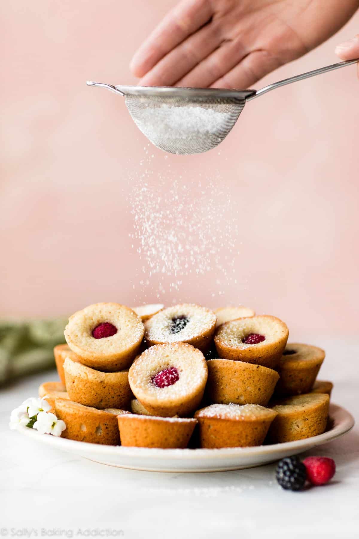 dusting tops of mini muffin tea cakes with powdered sugar