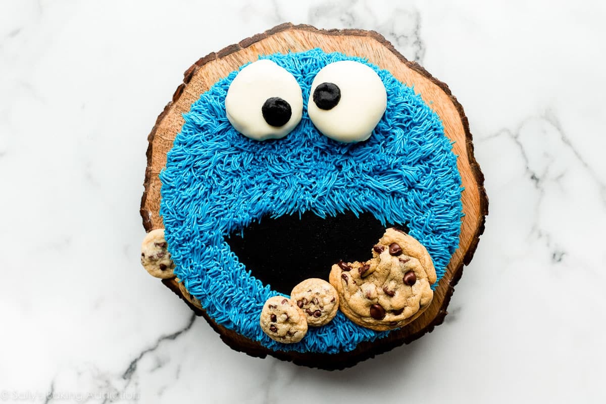 homemade decorated cookie monster cake on wooden cake stand.