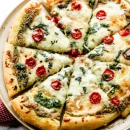 baked and sliced pesto pizza with mozzarella cheese and tomatoes.