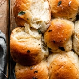 6 sage dinner rolls in glass baking pan.