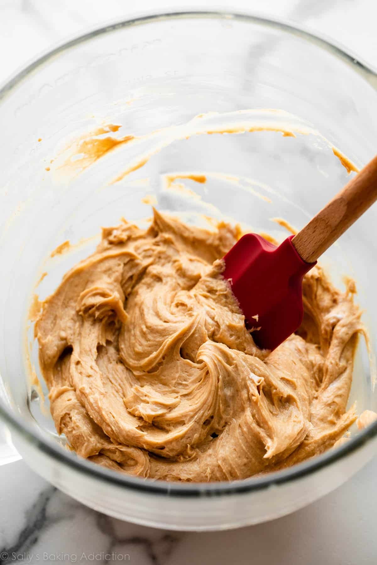 peanut butter mixture in glass bowl with red spatula.