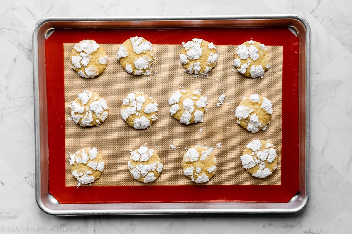 baked lemon crinkle cookies on lined baking sheet.
