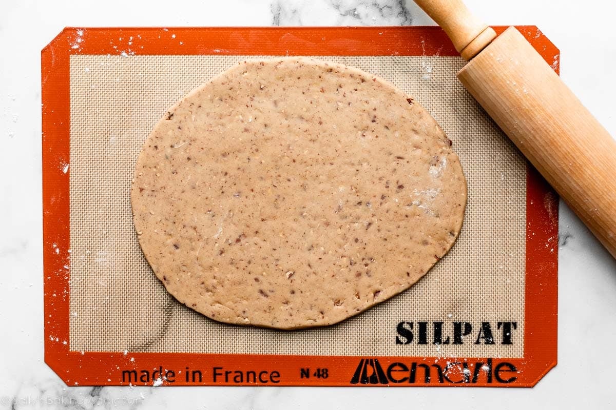 rolled out pecan-speckled dough on silicone baking mat.