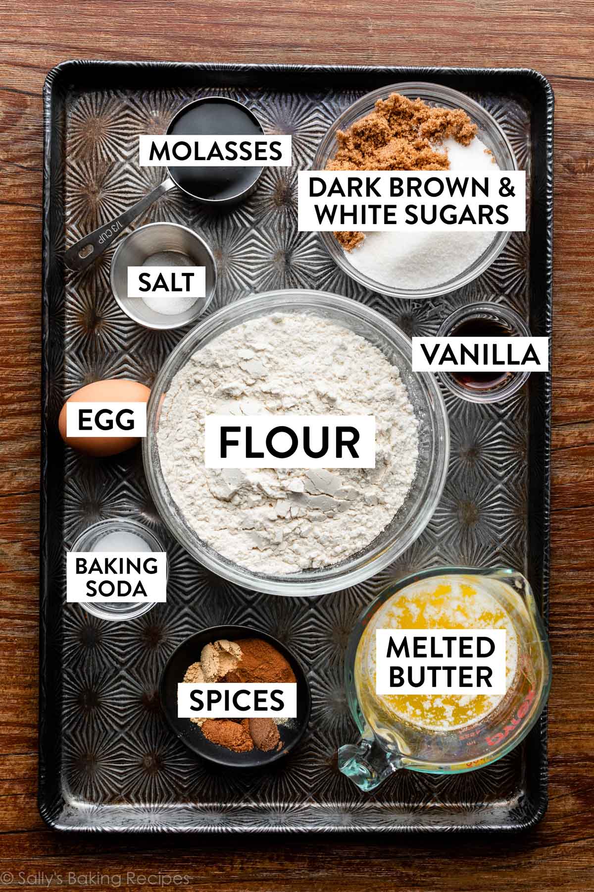ingredients on baking sheet including flour, melted butter, egg, vanilla, spices, and molasses.