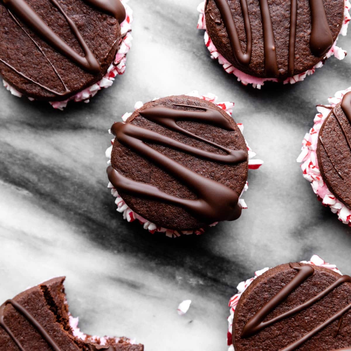 chocolate sandwich cookies with pink frosting rolled in crushed candy canes.