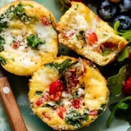 spinach and feta egg muffins on blue plate with berries in background.