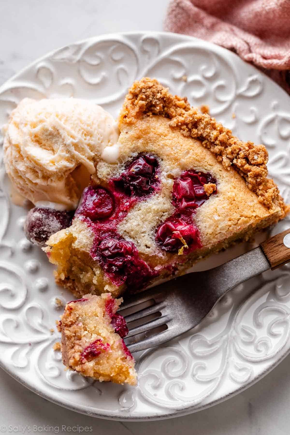 slice of cranberry almond frangipane tart with ice cream on white plate.