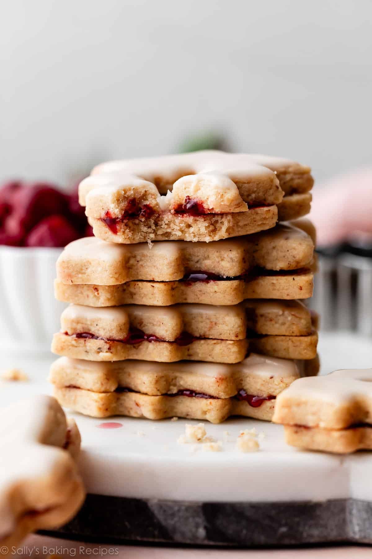 stack of cherry almond linzer cookies on white marble slab.