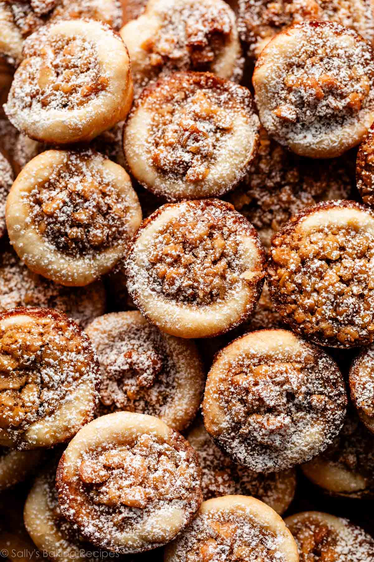 close-up of maple walnut tassies with confectioners' sugar dusted on top.
