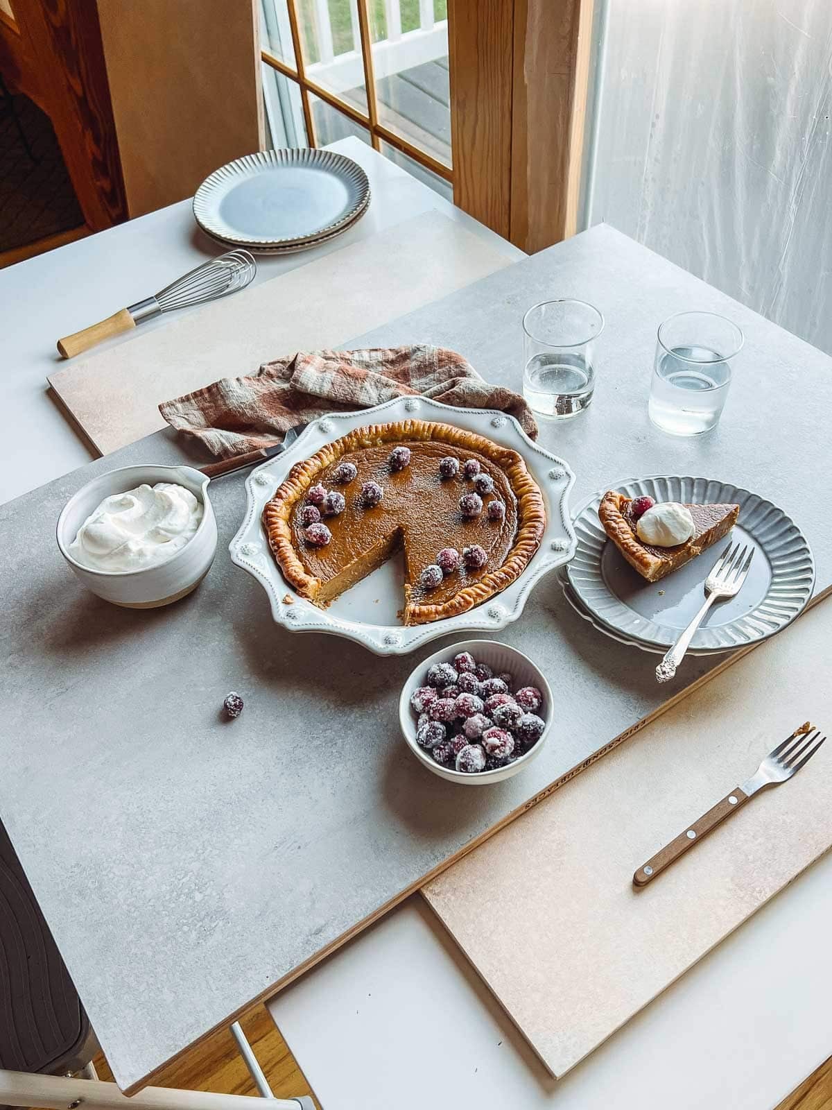 pumpkin pie on photography board with sugared cranberries.