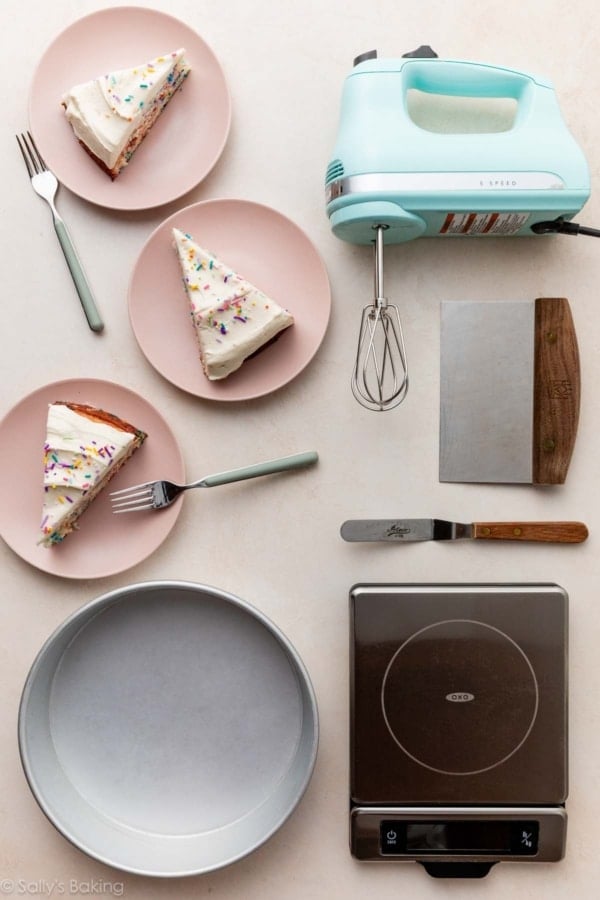 funfetti cake slices on pink plates with cake tools including a round cake pan, handheld mixer, and food scale.