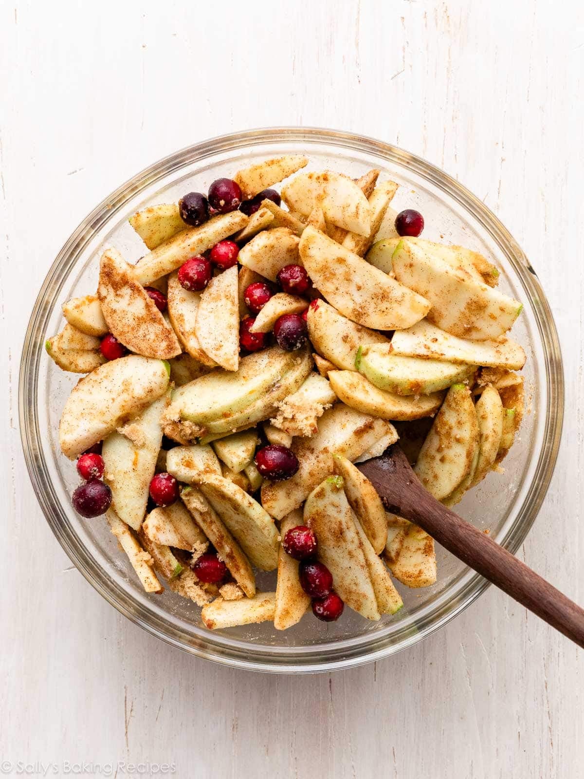 apples and cranberries with brown sugar and spices in glass bowl.