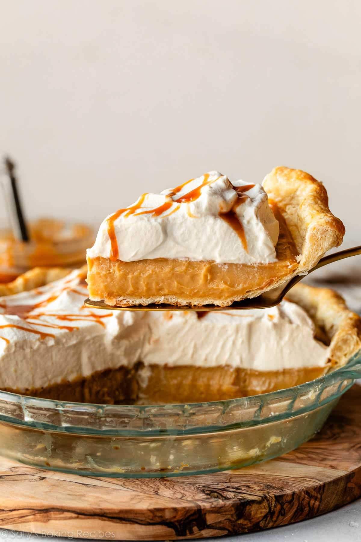 slice of butterscotch pie on pie server with whipped cream and salted caramel sauce.