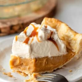 slice of butterscotch pie with whipped cream on top with fork bite taken out of the end.