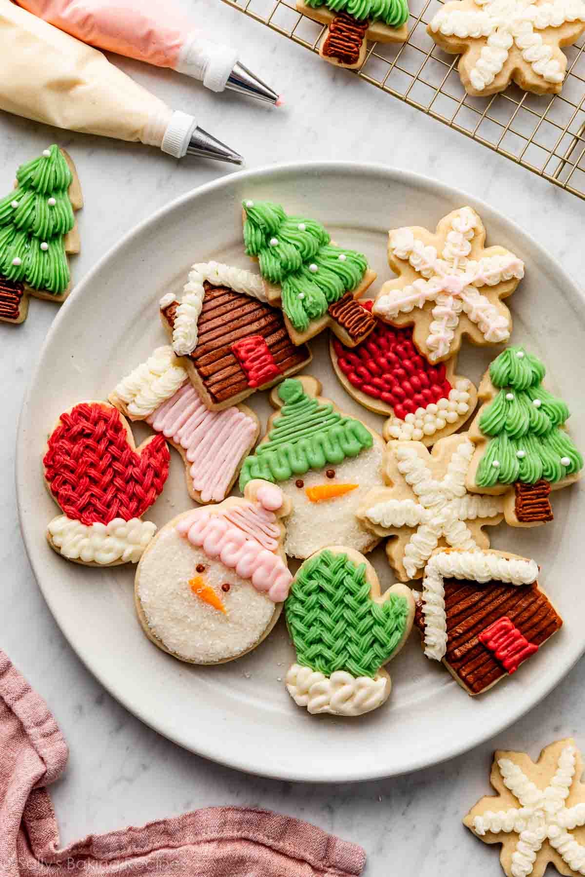 Christmas sugar cookies decorated with buttercream frosting on white plate.