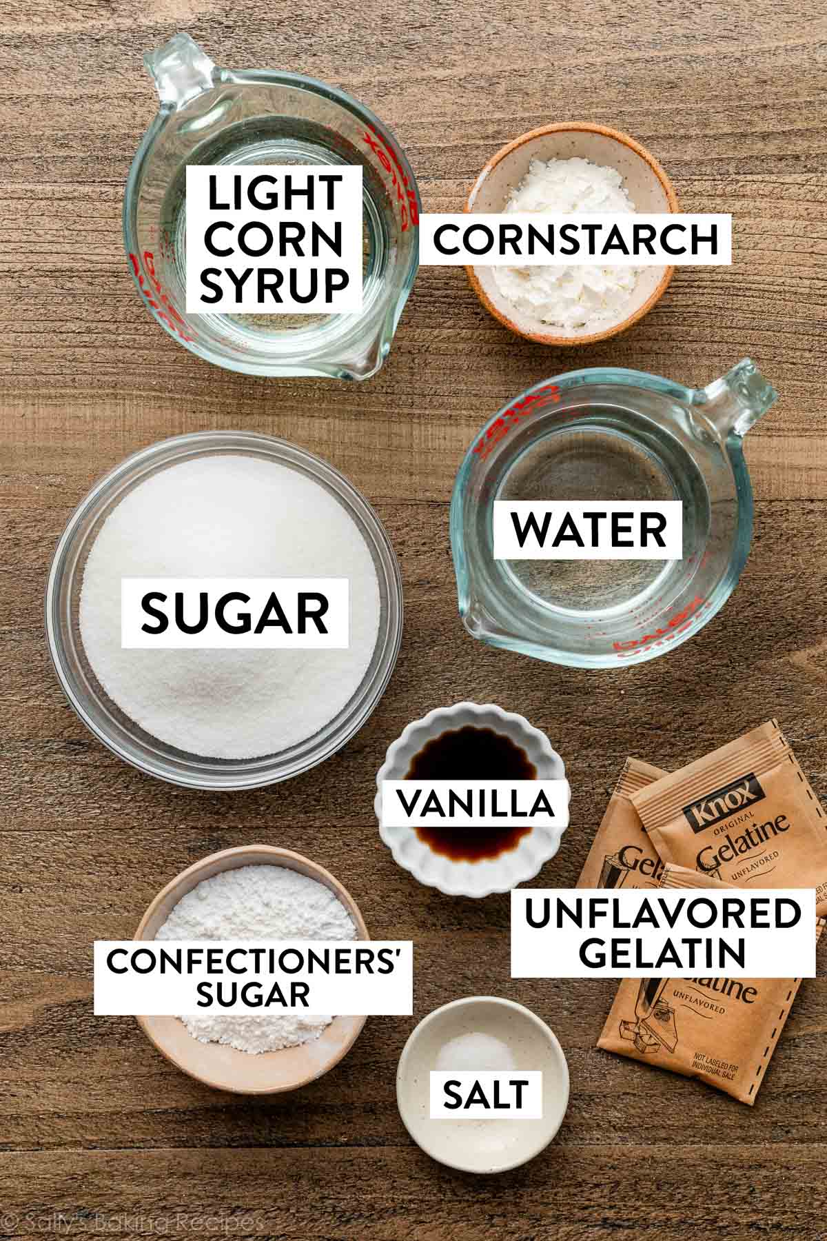 ingredients on wooden surface including cornstarch, sugar, water, gelatin, corn syrup, and vanilla.