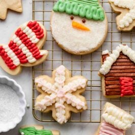 Christmas sugar cookies decorated with cookie decorating buttercream frosting on gold cooling rack.