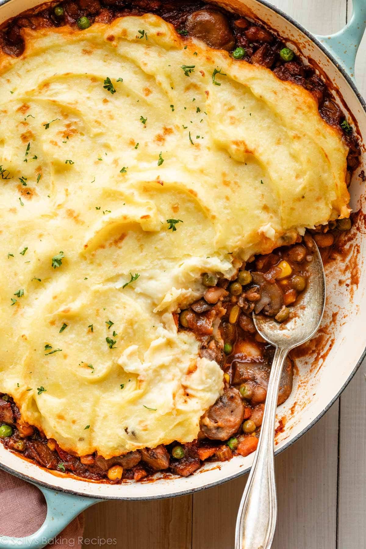 spoon in dish of vegetarian shepherd's pie with mashed potato topping.